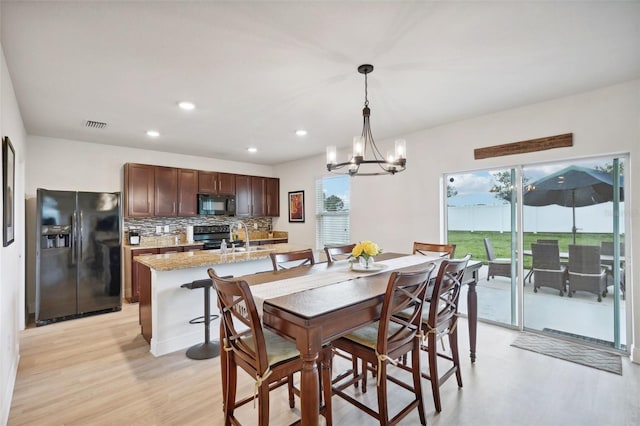 dining room featuring sink, light hardwood / wood-style floors, and a notable chandelier