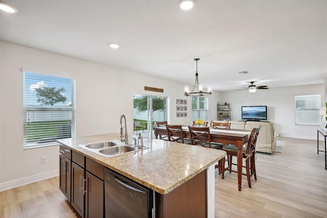 kitchen featuring black dishwasher, a kitchen island with sink, pendant lighting, ceiling fan with notable chandelier, and sink