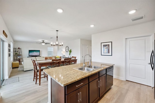 kitchen with dark brown cabinetry, dishwasher, an island with sink, sink, and hanging light fixtures