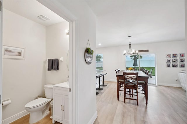 bathroom with hardwood / wood-style flooring, toilet, a notable chandelier, and a healthy amount of sunlight