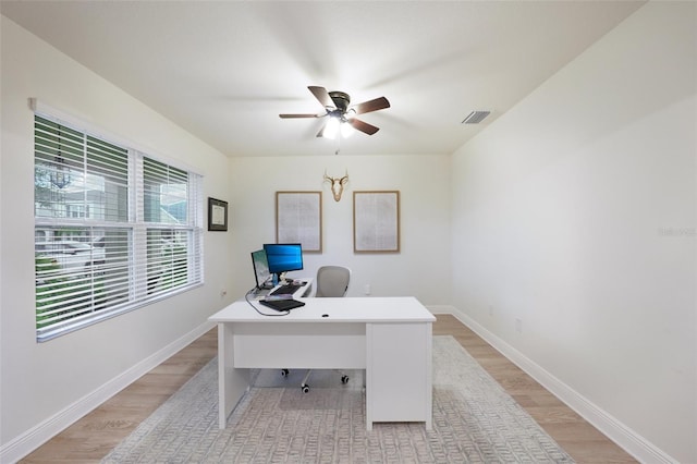 office featuring ceiling fan with notable chandelier and light hardwood / wood-style flooring