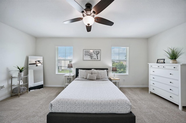 bedroom featuring ceiling fan, light colored carpet, and multiple windows