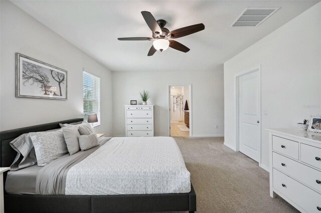 bedroom with ceiling fan, ensuite bathroom, and light colored carpet