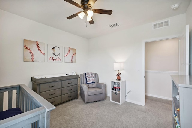 carpeted bedroom with ceiling fan and a crib