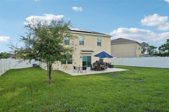 rear view of house with a lawn, central air condition unit, a patio area, and solar panels