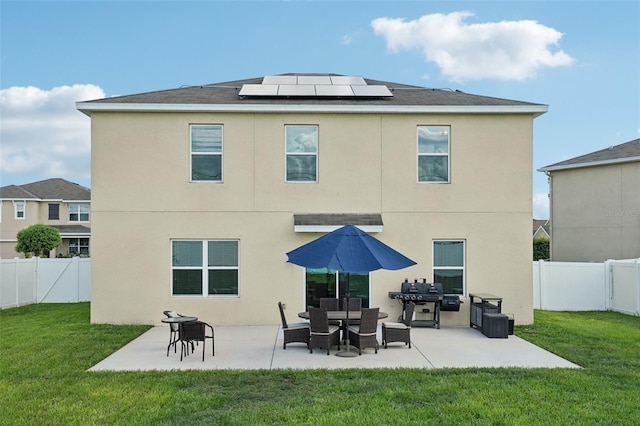 back of house with a lawn, solar panels, and a patio