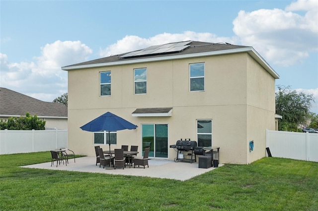 rear view of property with a patio area, a yard, and solar panels