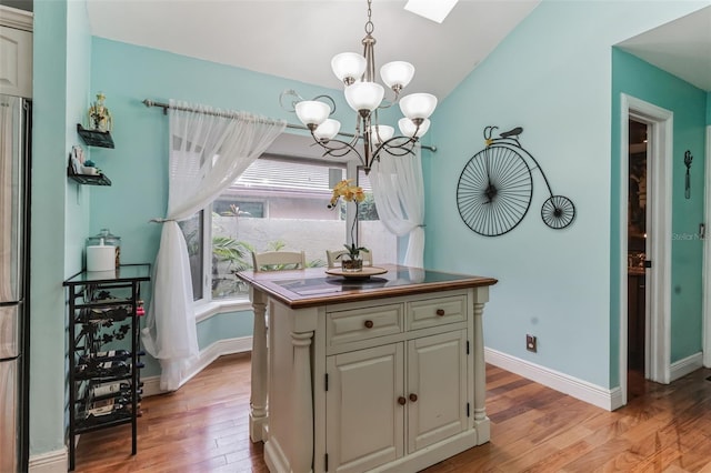 dining room with an inviting chandelier, light hardwood / wood-style floors, and lofted ceiling