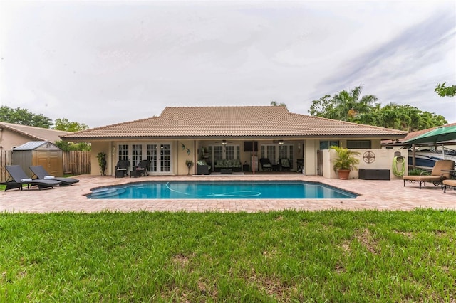 view of pool with ceiling fan, a patio, a shed, and a lawn