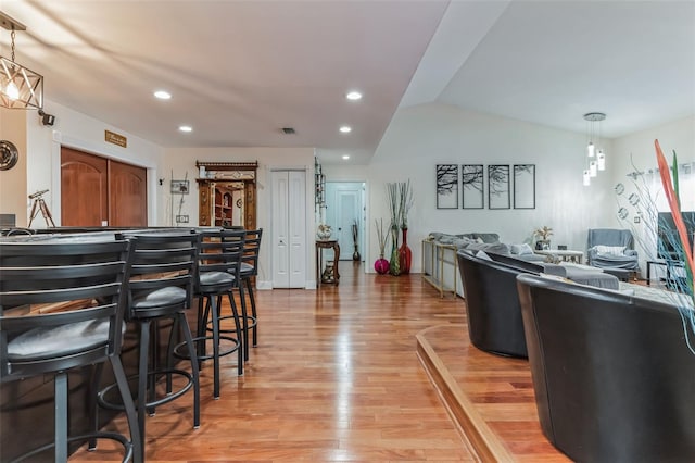 kitchen featuring vaulted ceiling, decorative light fixtures, a kitchen breakfast bar, and light hardwood / wood-style flooring