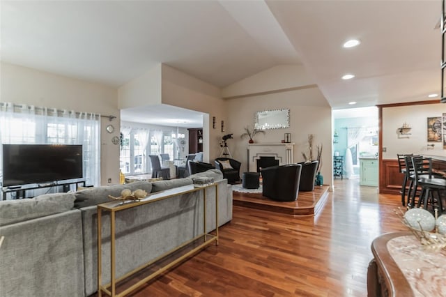 living room with hardwood / wood-style flooring, lofted ceiling, and a chandelier