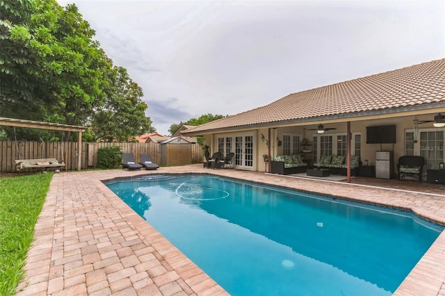 view of pool with a storage shed, a patio area, outdoor lounge area, and ceiling fan