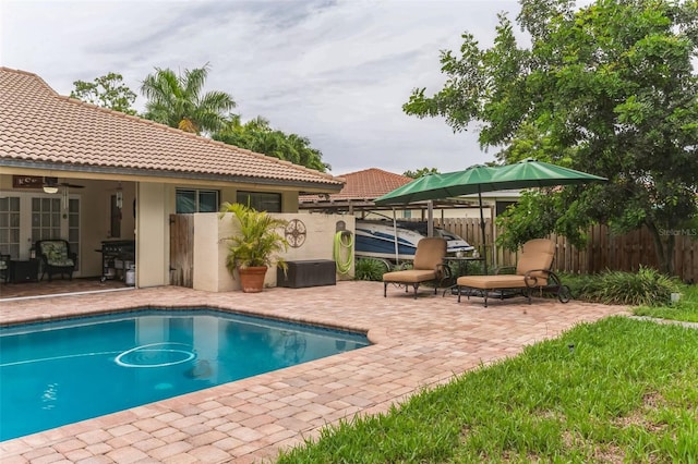 view of swimming pool featuring ceiling fan and a patio area