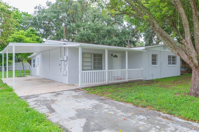 ranch-style house featuring a carport, a porch, and a front yard