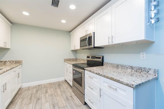 kitchen featuring light hardwood / wood-style floors, appliances with stainless steel finishes, white cabinetry, and light stone countertops