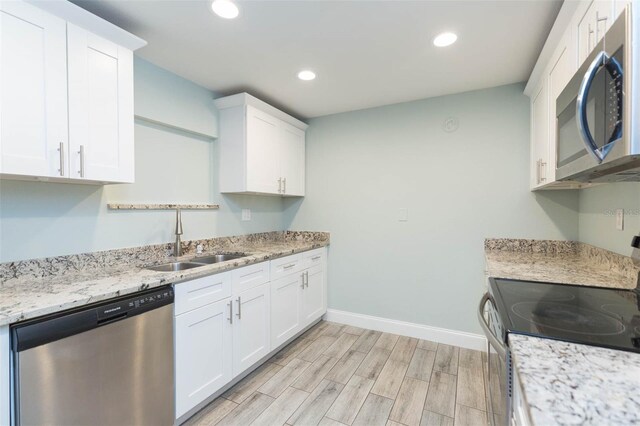 kitchen featuring white cabinetry, light wood-type flooring, appliances with stainless steel finishes, and sink