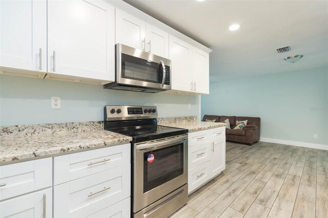 kitchen featuring light stone counters, light wood-type flooring, stainless steel appliances, and white cabinets