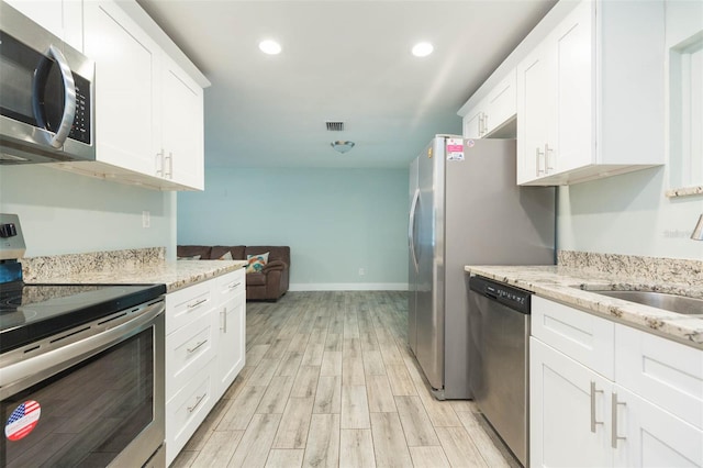 kitchen featuring white cabinets, stainless steel appliances, sink, and light wood-type flooring