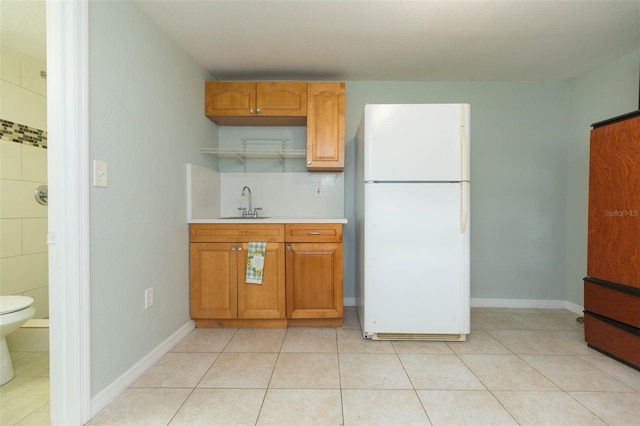 kitchen with sink, white refrigerator, and light tile patterned floors