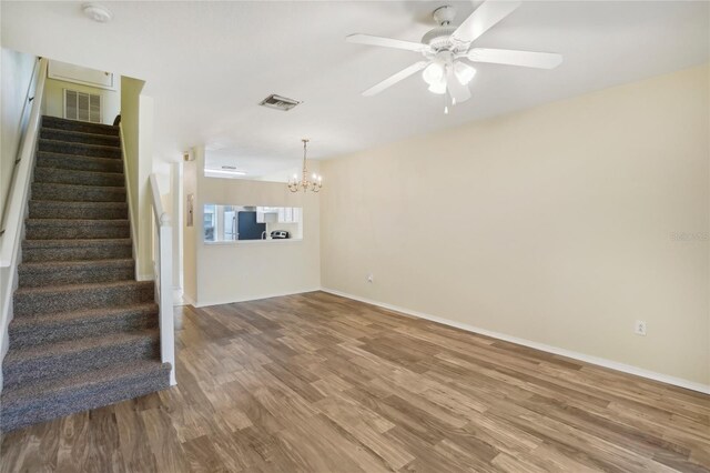 unfurnished living room with ceiling fan with notable chandelier and wood-type flooring