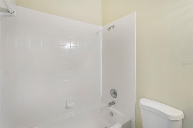 bathroom with tiled shower / bath combo and toilet