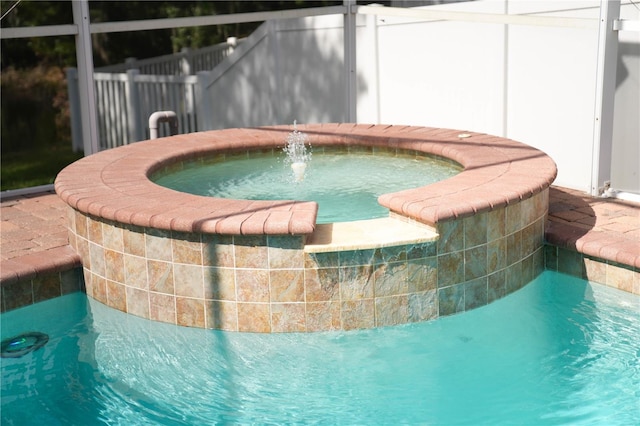 view of swimming pool with a lanai, an in ground hot tub, and pool water feature