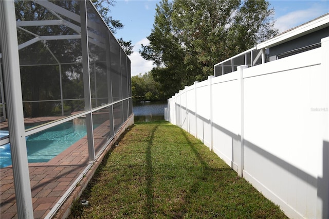 view of yard featuring a lanai, a fenced in pool, and a water view