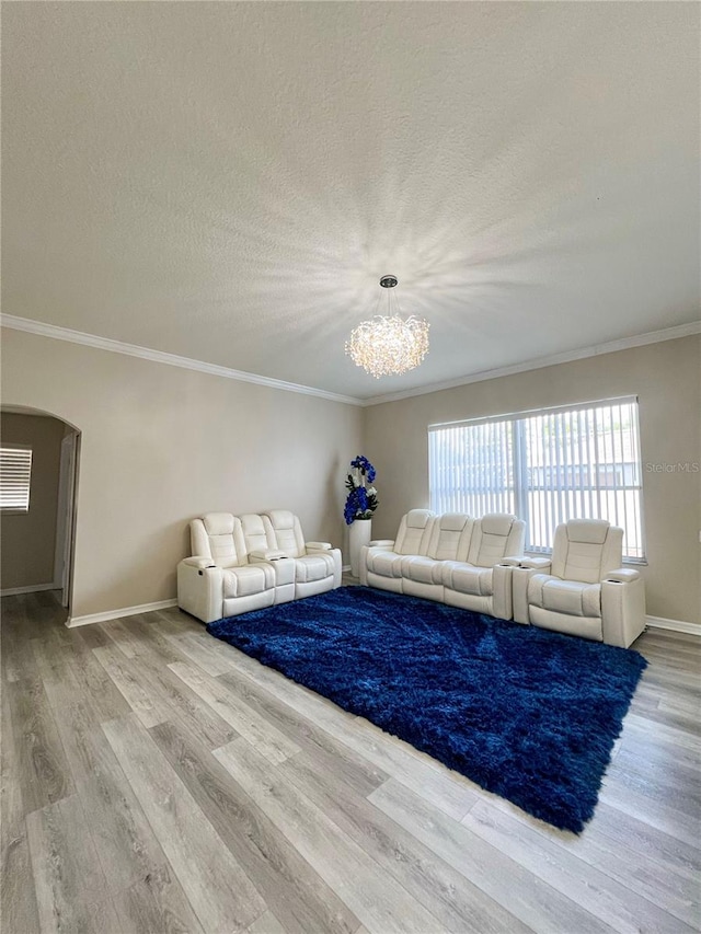 unfurnished living room with light wood-type flooring, a chandelier, and crown molding