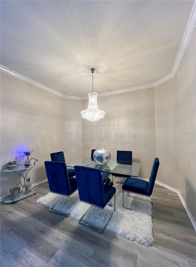 dining room with a textured ceiling, an inviting chandelier, wood-type flooring, and crown molding