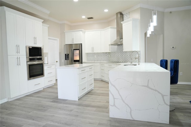 kitchen with stainless steel appliances, pendant lighting, sink, kitchen peninsula, and wall chimney exhaust hood