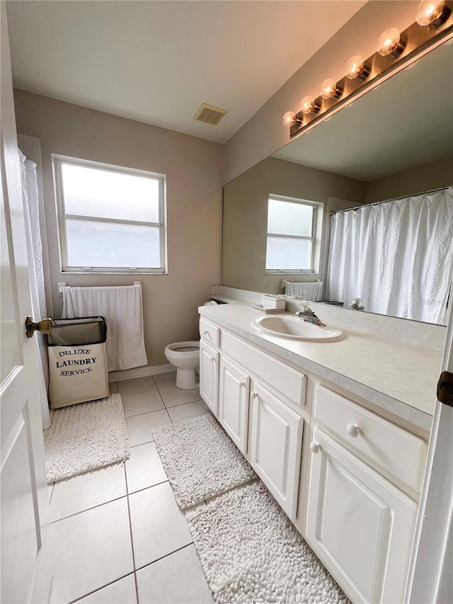 bathroom featuring tile patterned flooring, vanity, a healthy amount of sunlight, and toilet