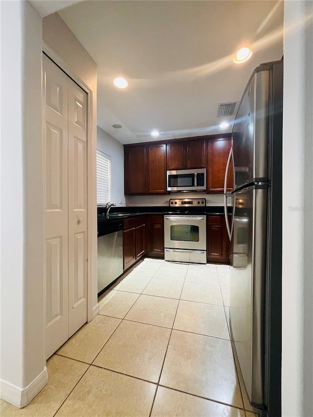 kitchen featuring dark brown cabinets, stainless steel appliances, and light tile patterned flooring