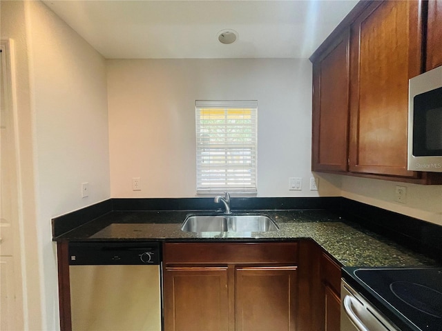 kitchen with stainless steel appliances, sink, and dark stone countertops