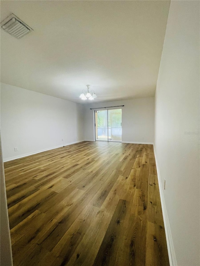 unfurnished room featuring a chandelier and hardwood / wood-style floors