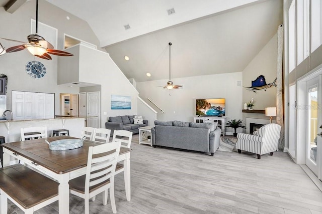 dining room with high vaulted ceiling, light wood-type flooring, and ceiling fan