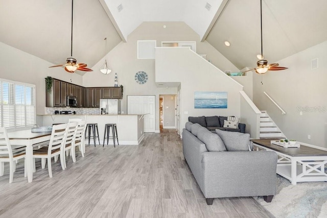 living room featuring high vaulted ceiling, light hardwood / wood-style flooring, and ceiling fan