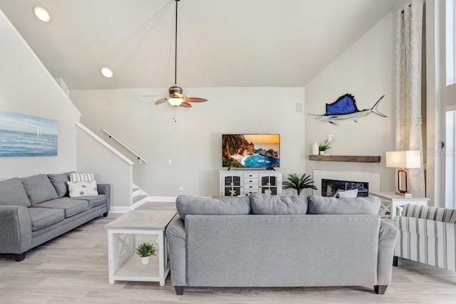 living room featuring a high ceiling, light hardwood / wood-style flooring, and ceiling fan