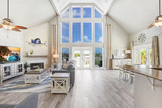 living room with french doors, plenty of natural light, ceiling fan, and high vaulted ceiling