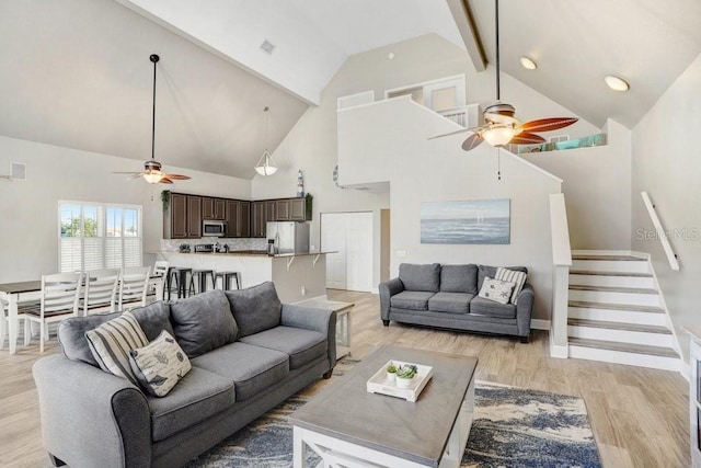 living room with ceiling fan, beam ceiling, light hardwood / wood-style flooring, and high vaulted ceiling