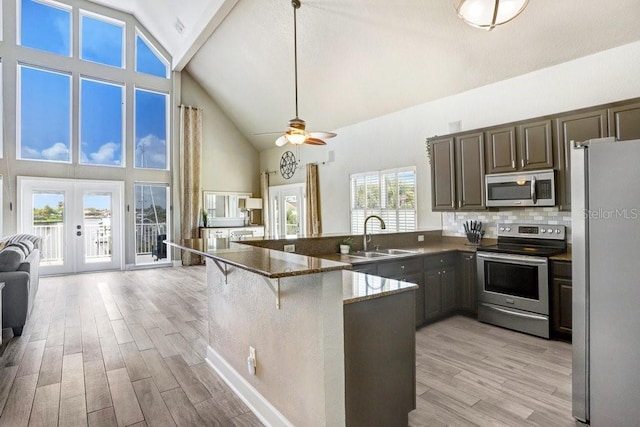 kitchen with stainless steel appliances, high vaulted ceiling, sink, and kitchen peninsula