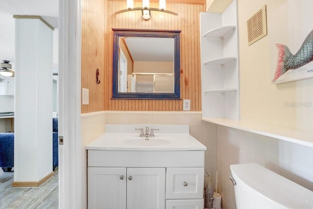 bathroom with vanity, toilet, and tile walls