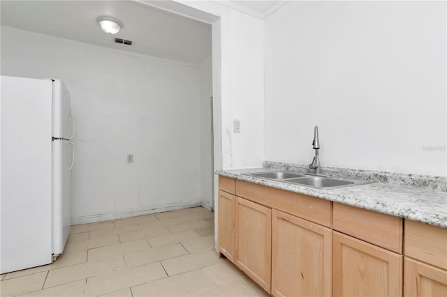 kitchen featuring sink, crown molding, light brown cabinets, and white fridge