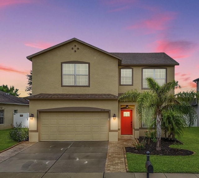 view of front of home featuring driveway, an attached garage, and stucco siding