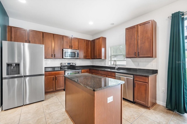 kitchen with a center island, stainless steel appliances, sink, decorative backsplash, and dark stone countertops