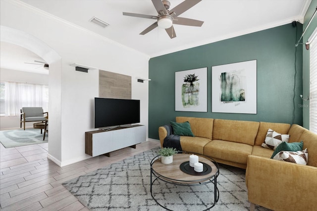 living room featuring arched walkways, crown molding, visible vents, ceiling fan, and wood finished floors