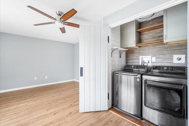 clothes washing area with light hardwood / wood-style flooring, washer and clothes dryer, cabinets, ceiling fan, and wooden walls