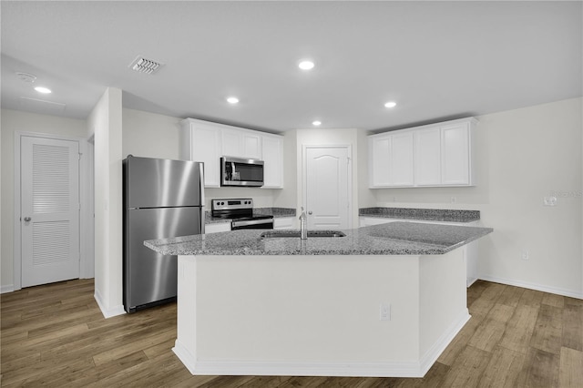 kitchen with sink, appliances with stainless steel finishes, wood-type flooring, and a center island with sink