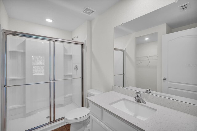 bathroom with walk in shower, hardwood / wood-style flooring, toilet, and vanity