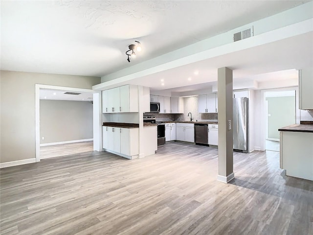 kitchen with light hardwood / wood-style floors, white cabinetry, and appliances with stainless steel finishes