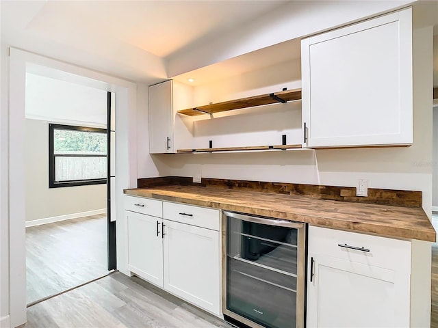 kitchen featuring white cabinets, light hardwood / wood-style flooring, wooden counters, and wine cooler